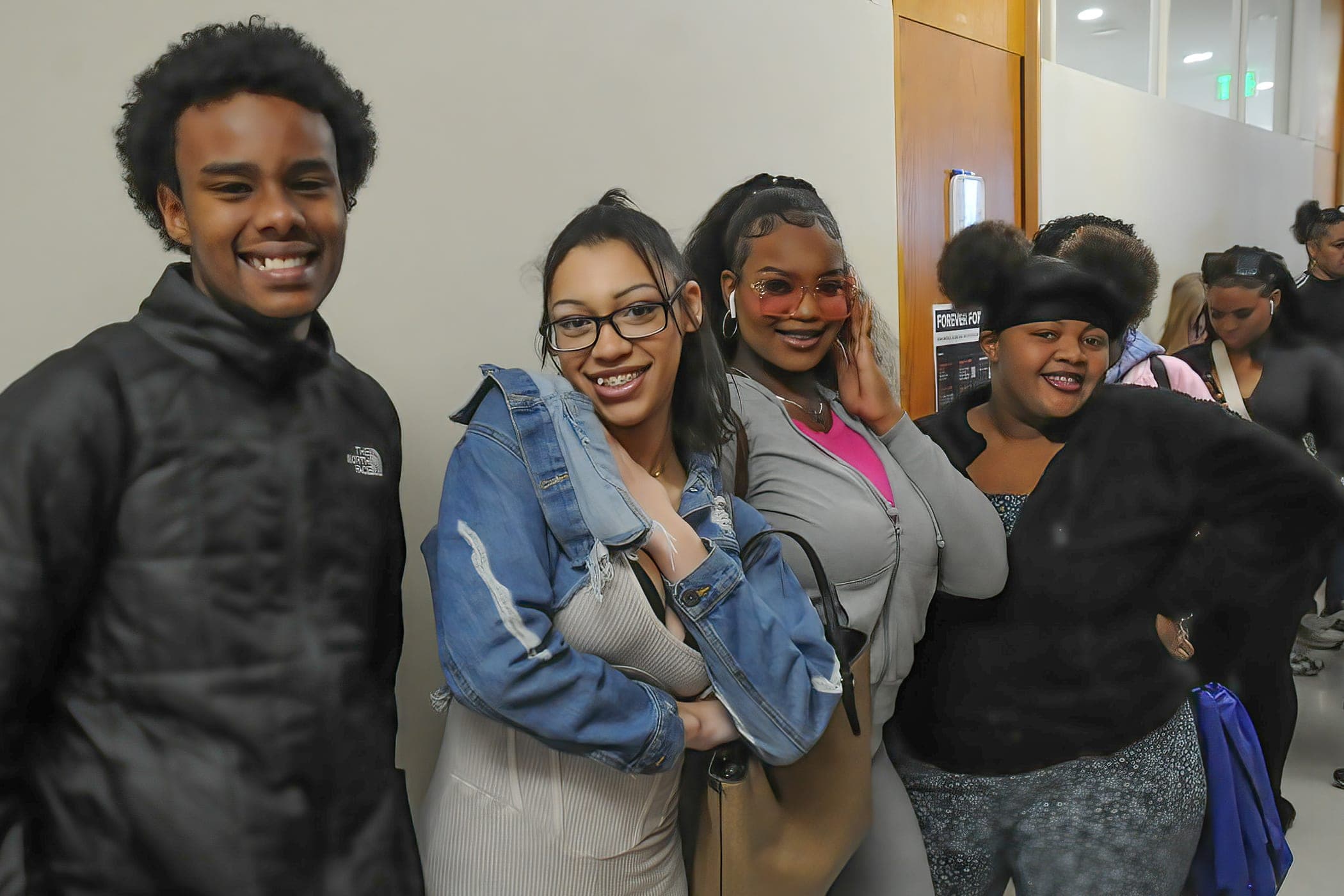 Four smiling students posing together in a college hallway at the 2024 AAYLC conference